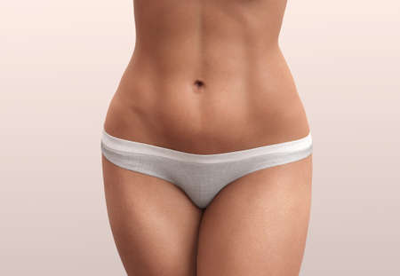 Abdominal press, flat belly. Woman body beauty healthcare. Close up of female body in beige panties.の写真素材