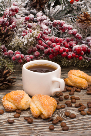 Cup of coffee, coffee beans, cookies, fir branch in snow on wooden backgroundの写真素材