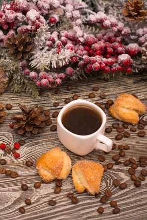 Cup of coffee, coffee beans, cookies, fir branch in snow on wooden backgroundの写真素材