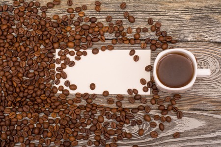 Coffee beans, cup of coffee, blank for text, on wooden tableの写真素材