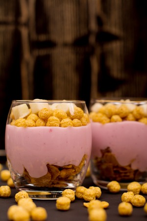 Yogurt desserts with muesli and slices of apple on dark wooden backgroundの写真素材