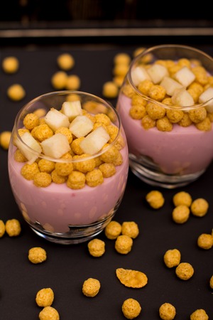 Yogurt desserts with muesli and slices of apple on dark wooden backgroundの写真素材