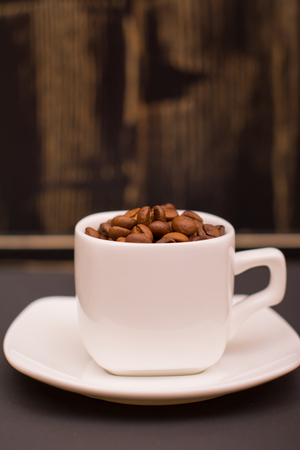 Coffee beans in a white cup on a dark wooden backgroundの写真素材
