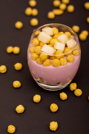 Yogurt desserts with muesli and slices of apple on dark wooden backgroundの写真素材