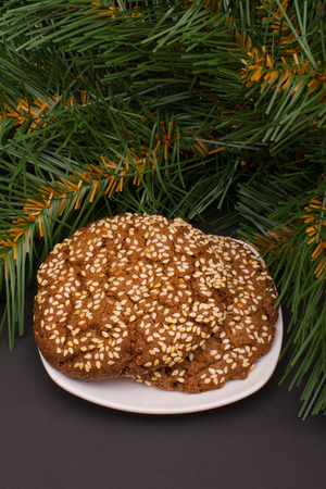 Cookies with sesame seeds and fir branch on a dark backgroundの写真素材