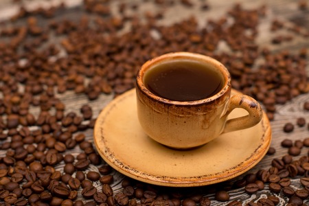 Small cup of coffee, roasted coffee beans on wooden backgroundの写真素材
