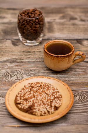 Small cup of coffee, glass with roasted coffee beans, cookies with sesame seedson wooden backgroundの写真素材