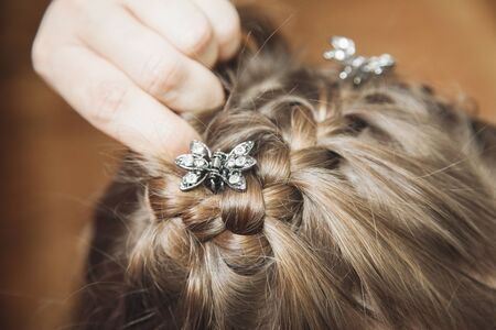 Photo Mom weaves braids daughter at homeの写真素材