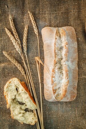 Freshly baked wheat bread, homemade cakes, still life with bread, crisp loaf of bread, still life on a rustic background, top view, rustic bread, roll, loaf.の写真素材