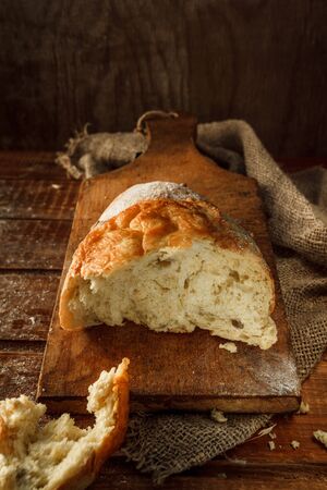 Freshly baked wheat bread, homemade cakes, still life with bread, crisp loaf of bread, still life on a rustic background, top view, rustic bread, roll, loaf.の写真素材