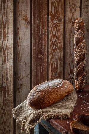 Freshly baked wheat bread, homemade cakes, still life with bread, crisp loaf of bread, still life on a rustic background, top view, rustic bread, roll, loaf.の写真素材