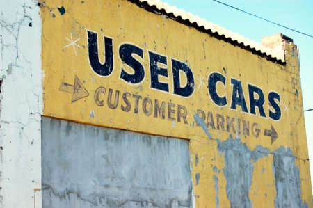 Old downtown building with used cars painted on sideの写真素材