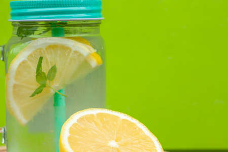 Glass with lemonade or mojito cocktail with lemon and mint, cold refreshing drink or beverage with...