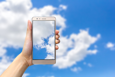 hand holding smartphone on blue sky backgroundの写真素材