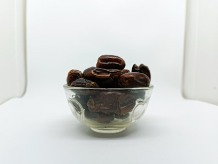 Dried dates in a glass bowl on white background. Selective focus.