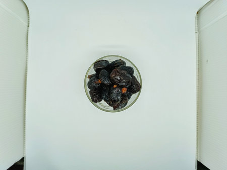 Dried plums in a glass vase on a white backgroundの写真素材