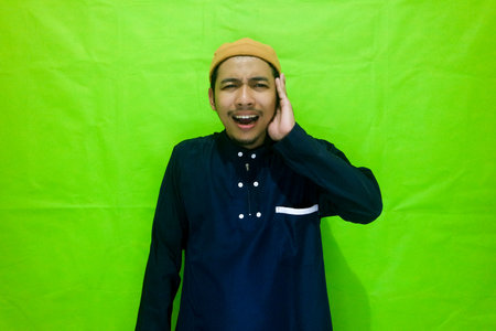 Religious Muslim man reads in the ear azan or iqamah isolated over green backgroundの写真素材