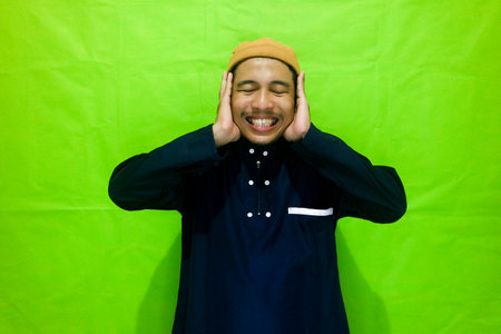 Religious Muslim man reads in the ear azan or iqamah isolated over green backgroundの写真素材