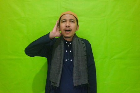 Religious Muslim man reads in the ear azan or iqamah isolated over green backgroundの写真素材