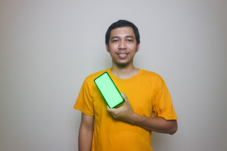Happy smiling young Asian man showing mobile phone on white