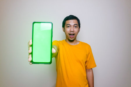 Happy smiling young Asian man showing mobile phone on white