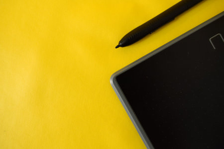 flat lay of cropped graphic creative pen tablet, with copy space on yellow backgroundの写真素材