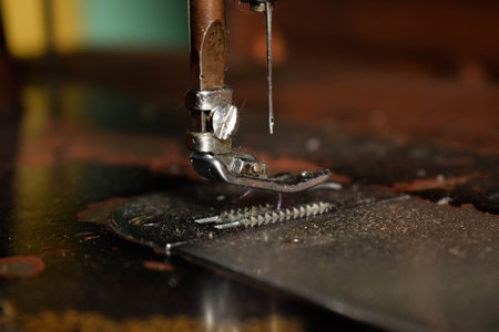 Close up sewing machine with needle on wood table, antique sewing machine with dustの写真素材