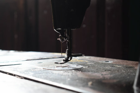 Close up sewing machine with needle on wood table, antique sewing machine with dust