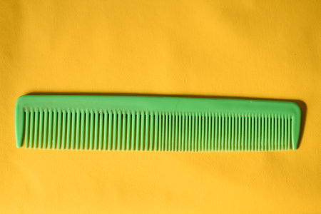 a green comb isolated on yellow backgroundの写真素材