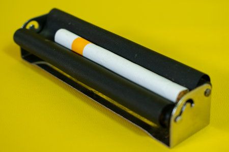 A black metal roller for make cigarette, cigarette roller handmade on yellow backgroundの写真素材