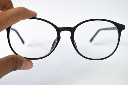 Hand hold Black frame eyeglasses unisex isolated on white backgroundの写真素材