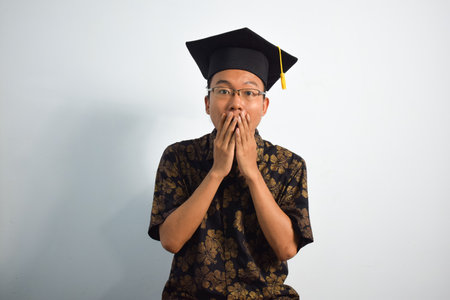 Expressive of Adult indonesia male wear batik, toga cup or graduation hat and eyeglasses isolated on...