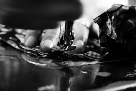 Vintage Black and White Close up Senior Female Tailor Sewing batik indonesian fabric into cloth,...