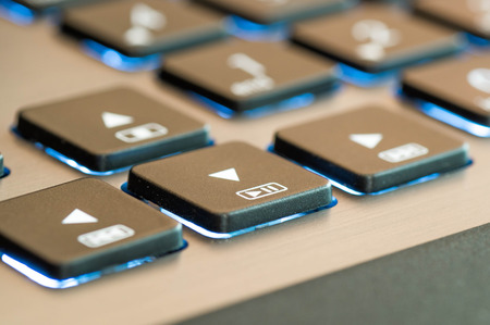 Lateral close up shot of a blue illuminated keyboard play sign