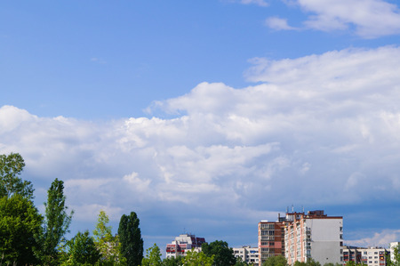 Apartment block in distance with trees and blue skyの写真素材