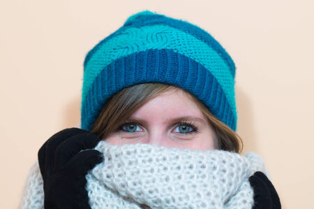 Beautiful girl looking directly in the camera and smiling, while wearing black gloves blue beanie...