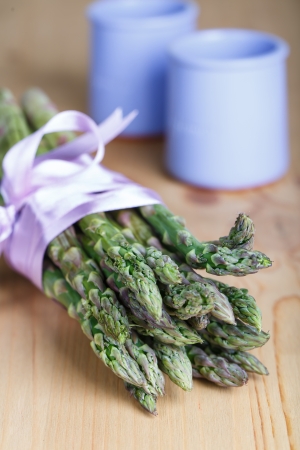 Bunch of fresh green asparagus spears tied with ribbon on a rustic wooden tableの写真素材