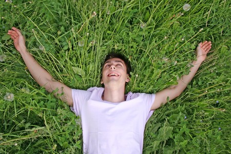 young man lies on grass and laughingの写真素材