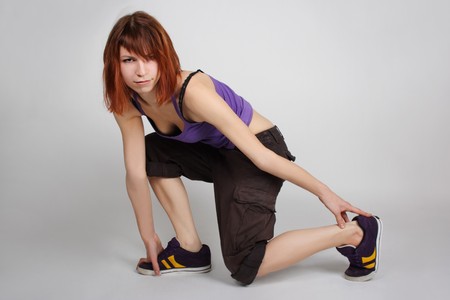 young redhead girl in hip-hop clothes sitting on one knee and looking at camera, full bodyの写真素材