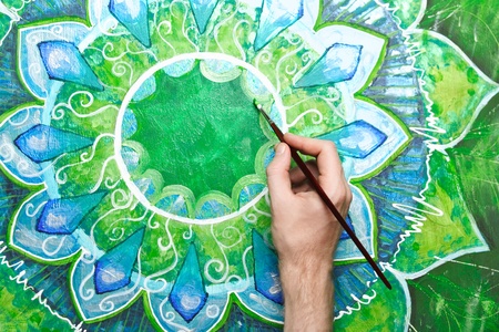 man painting bright green picture with circle pattern, mandala of anahata chakraの写真素材