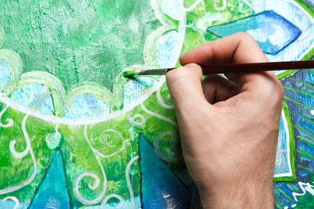 closeup of man painting green picture with circle pattern, mandala of anahata chakraの写真素材