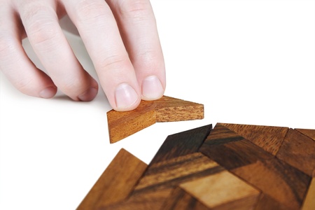 closeup of human hand assembling wooden square puzzle, isolatedの写真素材