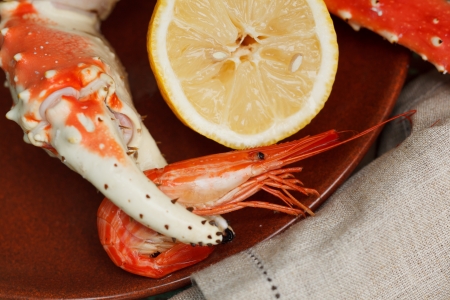Crab claw grasping a shrimp served on a seafood platter with lemon garnishの写真素材