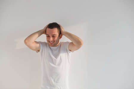 Handsome young man standing , wearing white t-shirt and pants  Studio shot, natural light の写真素材