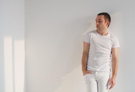 Handsome young man standing , wearing white t-shirt and pants  Studio shot, natural light の写真素材