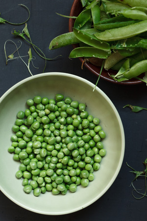Plate of fresh peeled peas on black table. Rustic styleの写真素材