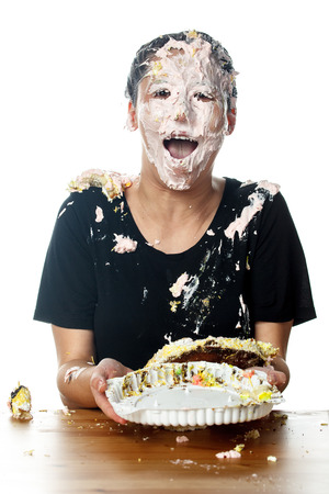 Portrait of happy woman with cake on her faceの写真素材