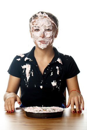 Portrait of happy woman with cake on her faceの写真素材