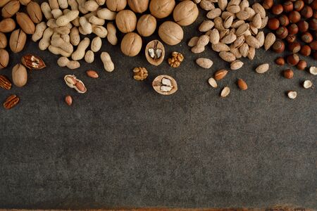 frame made of different types of nuts on stone background. Top view. Copy space