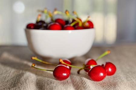 Cherries with full bowl in the background and shining light (selective focus)の写真素材